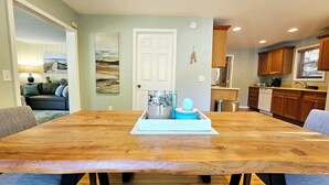 A spacious dining area with a wooden table, blue cushioned chairs, and a decorative centerpiece. - Vintage charm, modern comfort! Lakeshore retreat 3 mins to the beach! (Muskegon)