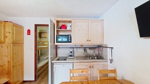 A compact kitchen with wooden cabinets, a microwave, a coffee maker, and a sink.