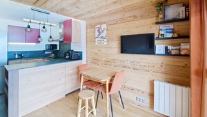 A modern kitchen with wooden cabinets, a built-in oven, and a dining area with a table and chairs. - VERONICA VR51 NATURE & MOUNTAIN 5 Pers (Châtel)
