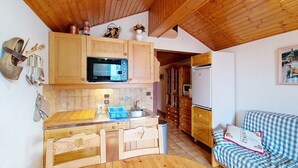 A compact kitchen with wooden cabinets, a microwave, a sink, and a dining table. - Biches BIA17 MOUNTAIN & QUIET 4 Pers. (Châtel)