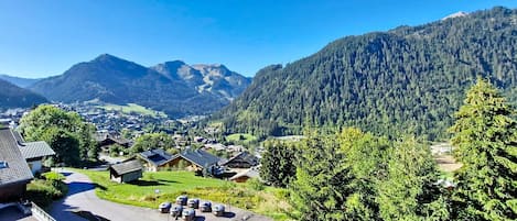 A residential area with houses, a parking lot, and a mountainous backdrop.