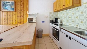 A compact kitchen with wooden cabinets, a microwave, a toaster, and a coffee maker. - Tavaillons TV31 SWIMMING POOL & CENTER 4 Pers (Châtel)