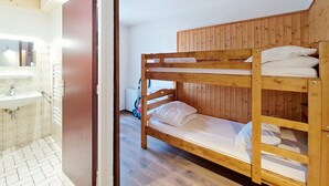 A bunk bed room with a wooden headboard, a white sink, and a tiled floor. - Tavaillons TV31 SWIMMING POOL & CENTER 4 Pers (Châtel)