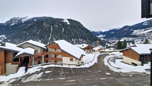 Un village enneigé, avec des bâtiments et une montagne en arrière-plan.