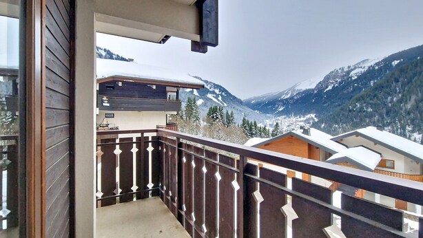 Un balcon doté d’une balustrade en métal, d’où l’on peut admirer un paysage montagneux.