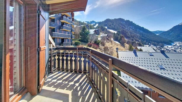 Een balkon met uitzicht op een berg en een stad.
