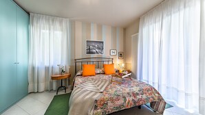 A bedroom with a bed, curtains, a nightstand, a lamp, and a framed picture on the wall. - Al Vittoriale 3 by Wonderful Italy (Gardone Riviera)