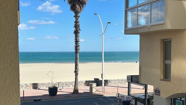Une vue sur une plage, prise depuis un bâtiment situé devant lequel passe une rue.