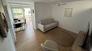 Un salon comprenant un canapé, une table à manger avec des chaises, un ventilateur de plafond et un téléviseur.