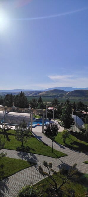 A resort with a swimming pool, lounge chairs, and a view of distant mountains.