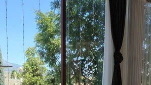 A room with a large window overlooking a garden, a dining table with chairs, and a bench by the window.