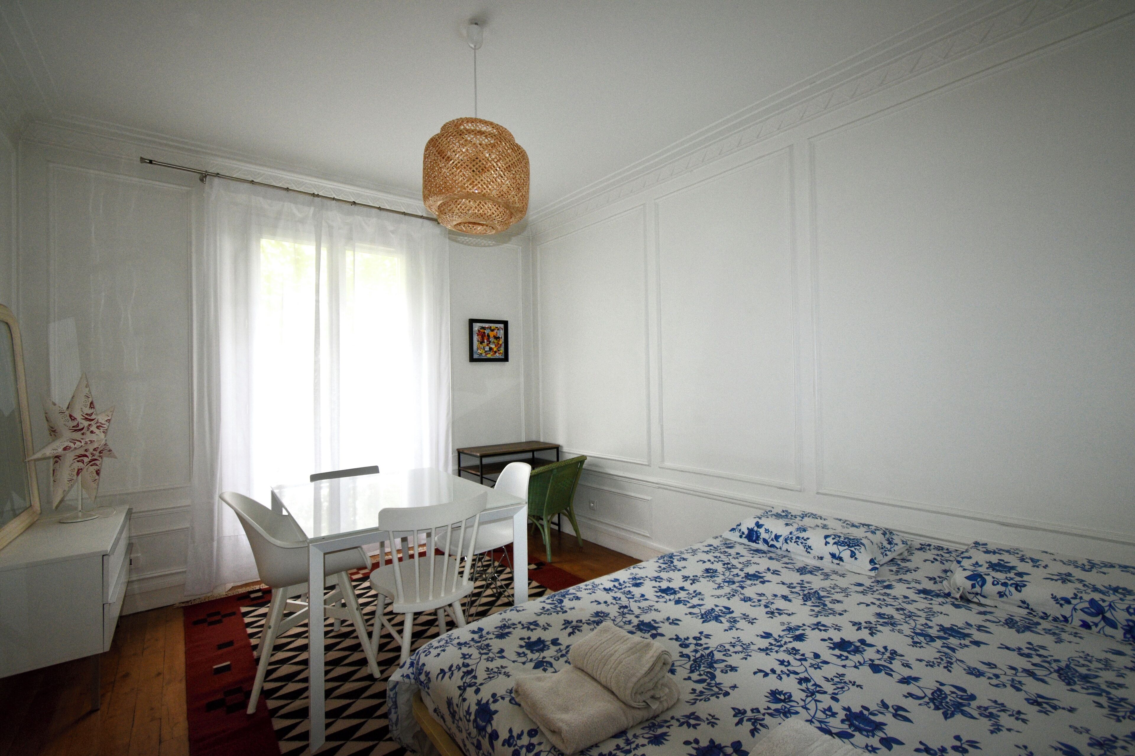 Een kamer met een bed, een bureau, een stoel en een hanglamp.