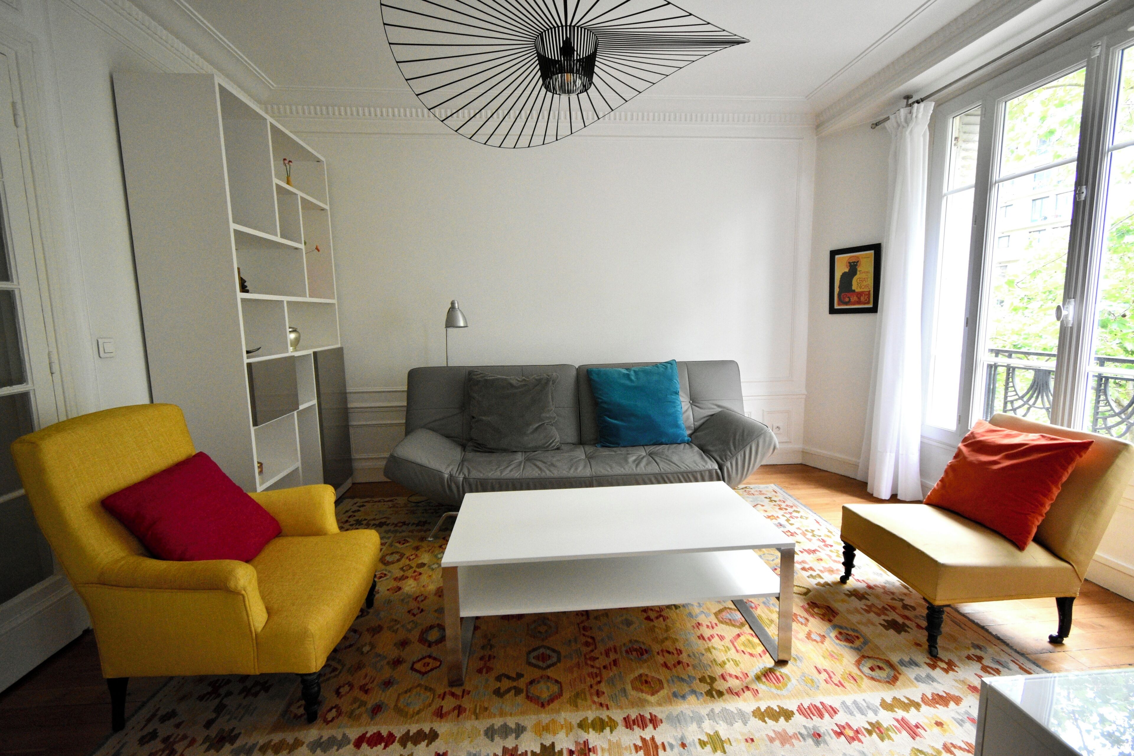 Un salon comprenant un canapé, des fauteuils, une table basse et une bibliothèque.