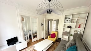 Un salon moderne comprenant un canapé, un fauteuil, une table basse, un téléviseur et un ventilateur décoratif.