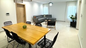 A modern living room with a wooden dining table, black chairs, a grey sofa, and a small round table. - KIA ORA APPART HOTEL (Abidjan)