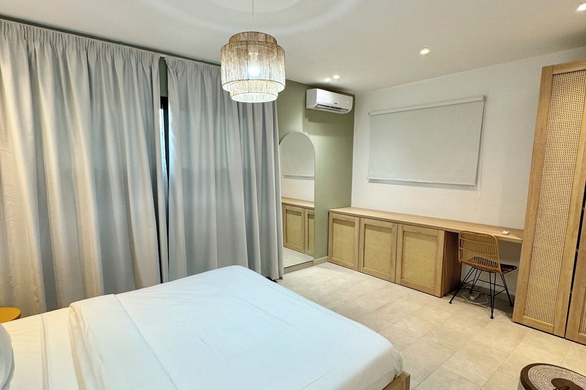 A modern bedroom with a large bed, a desk, and a chair.