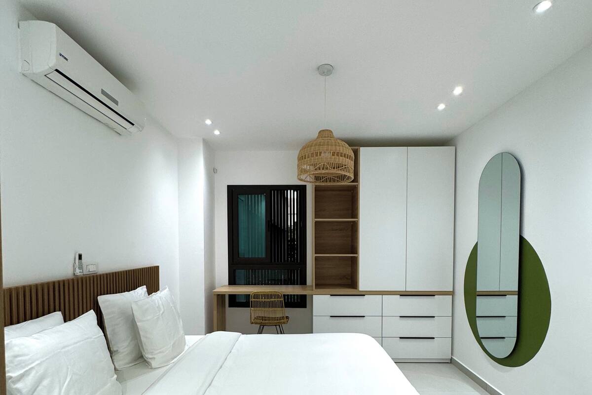 A modern bedroom with a large bed, built-in wardrobe, and a desk area.