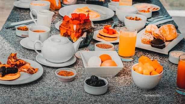 Une table de petit-déjeuner avec divers plats et boissons, donnant sur un espace piscine.