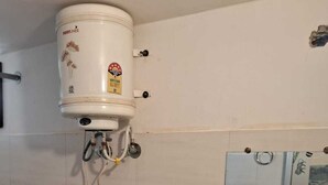 A bathroom with a toilet, sink, and a water heater mounted on the wall.