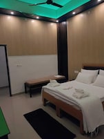 Un dormitorio moderno con cama, mesita de noche, banco y ventilador de techo.