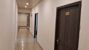 A hallway with a wooden door labeled "002" and a tiled floor.