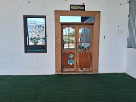 Una zona de recepción con puerta de madera, una ventana pequeña y un cartel sobre la puerta.