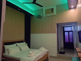 Un dormitorio con cama, ventilador de techo, aire acondicionado y vista al exterior a través de una ventana con cortinas.