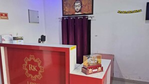 A reception desk with a red and white color scheme, a framed Buddha painting above it, and a calendar on the wall.