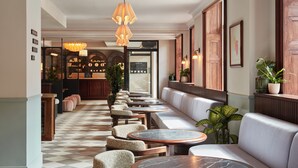 Un vestíbulo de hotel con suelo a cuadros, zonas de estar y un bar al fondo.