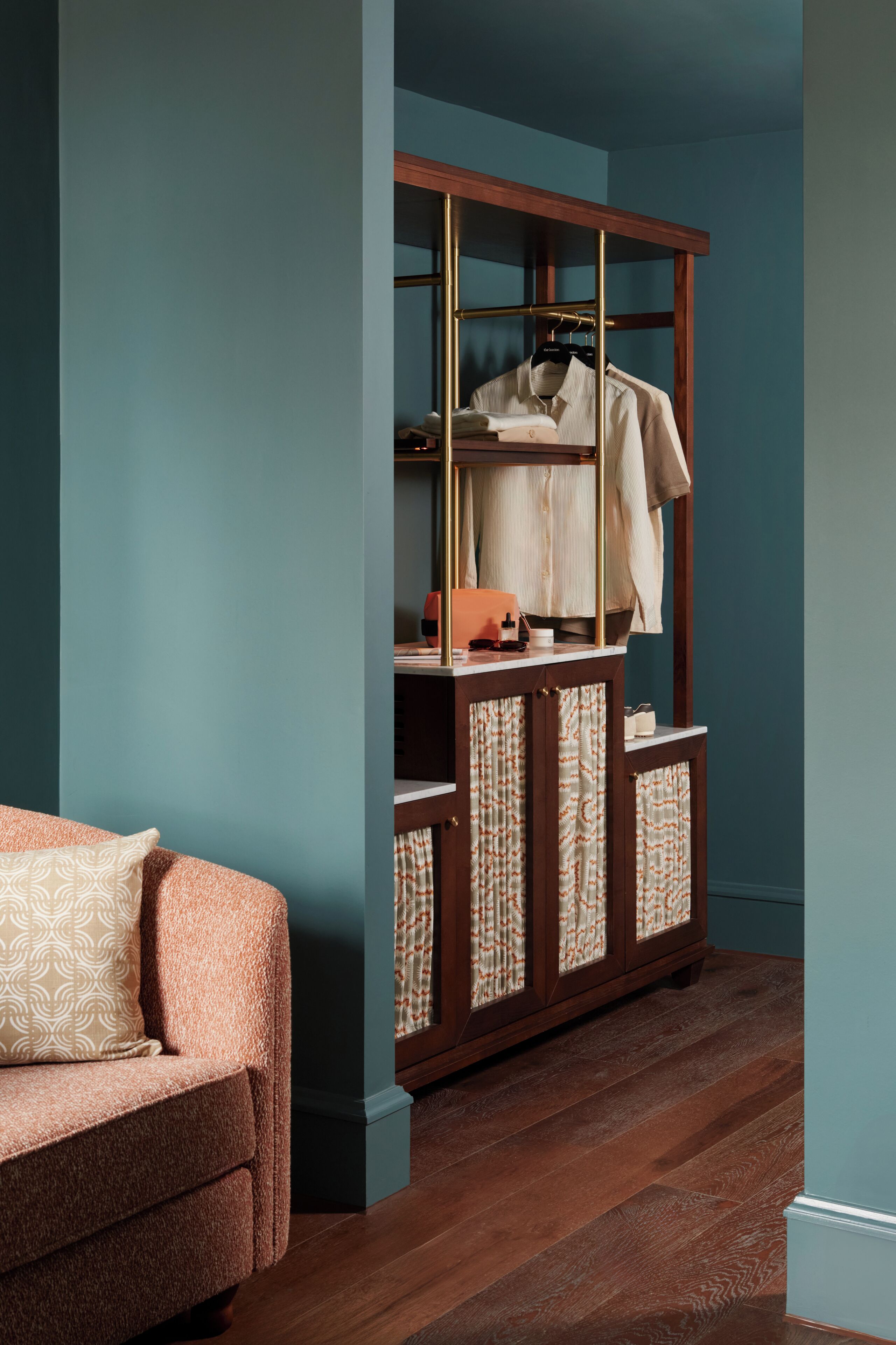 Une pièce avec une armoire en bois, un canapé à motifs et un mur de couleur turquoise.