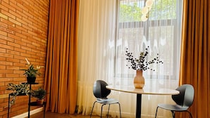 A dining area with a brick wall, a round table, two chairs, and a potted plant. - PoshSpot Apartments (Cluj-Napoca)