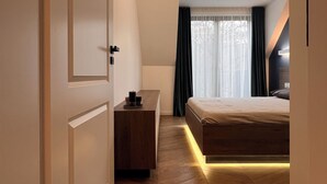 A modern bedroom with a wooden floor, a bed, a bedside table, and a nightstand. - PoshSpot Apartments (Cluj-Napoca)