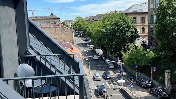 A street view from a balcony with cars, a pedestrian crossing, and buildings in the background. - PoshSpot Apartments (Cluj-Napoca)