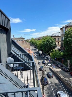 A street view from a balcony with cars, a pedestrian crossing, and buildings in the background. - PoshSpot Apartments (Cluj-Napoca)