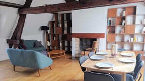 Un salon moderne avec un coin repas, des étagères en bois et une cheminée.