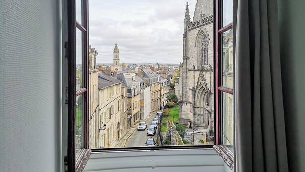 Une vue depuis une fenêtre donnant sur un paysage urbain, avec des bâtiments et une église.