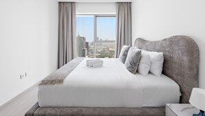 Una habitación de hotel moderna con una cama grande, vistas a la ciudad y un diseño minimalista.