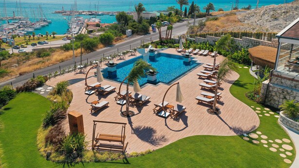 A resort with a swimming pool, lounge chairs, and a view of the sea.