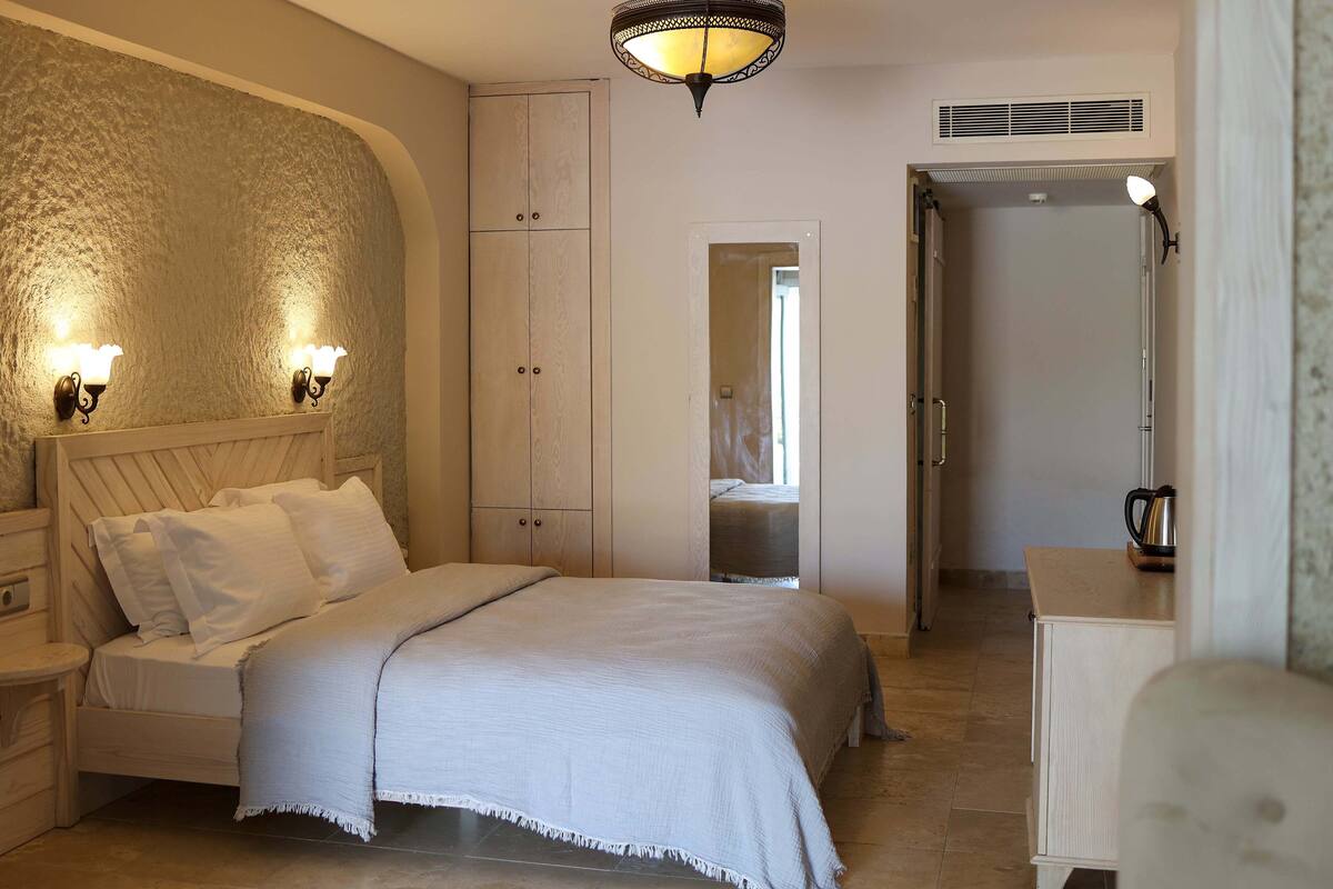 Un dormitorio con cama, mesitas de noche, un armario y un espejo.