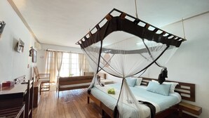 Un dormitorio con cama, piso de madera, un escritorio y una silla.