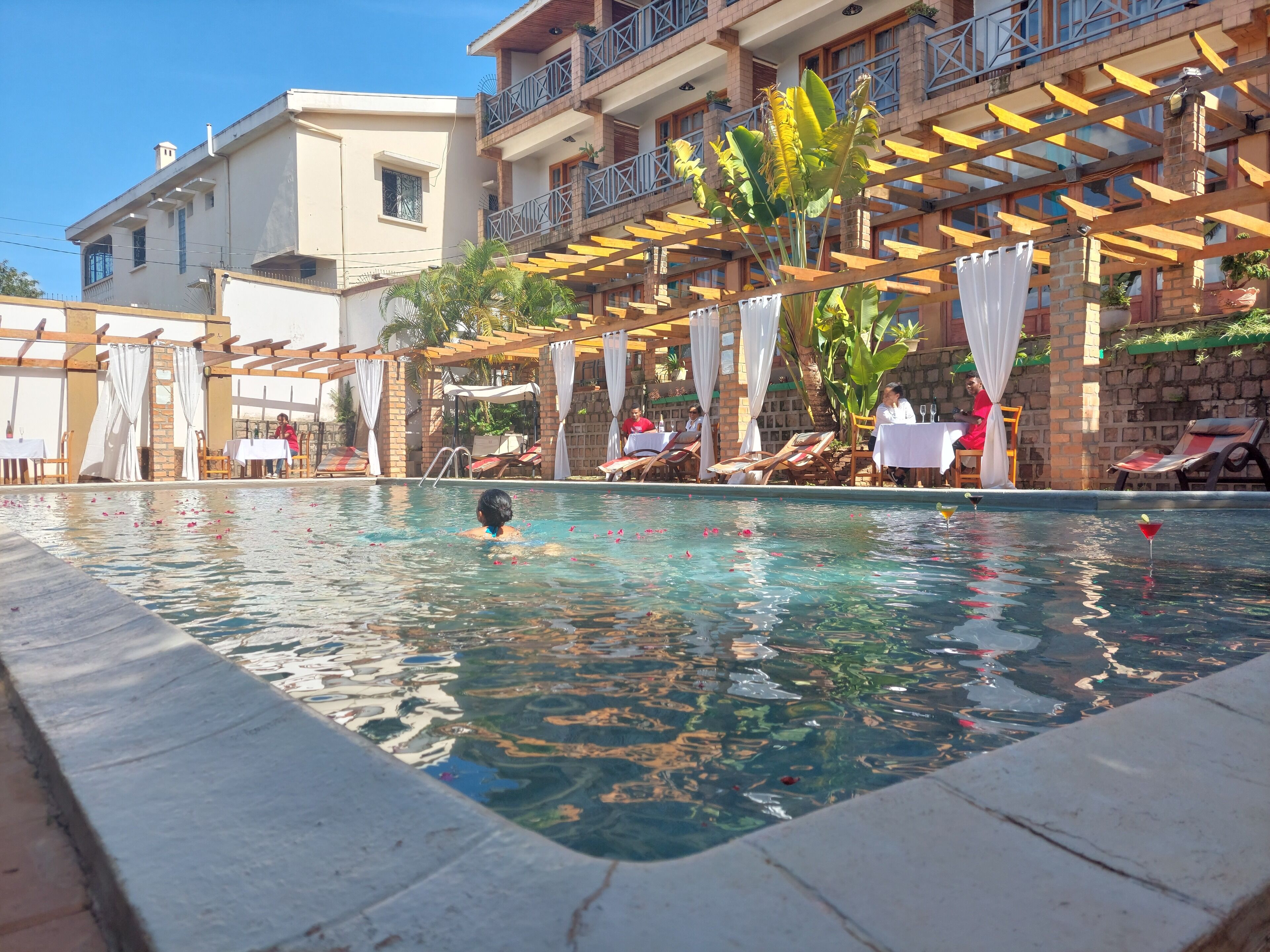 Une piscine à l’eau d’un bleu limpide, entourée de chaises longues et de parasols.