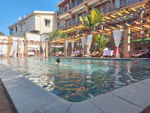 Una piscina amb una superfície d'aigua turquesa, envoltada de gandules i para-sols.