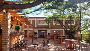 Un patio con baldosas hexagonales, muebles de madera y un edificio de ladrillo con ventanas.