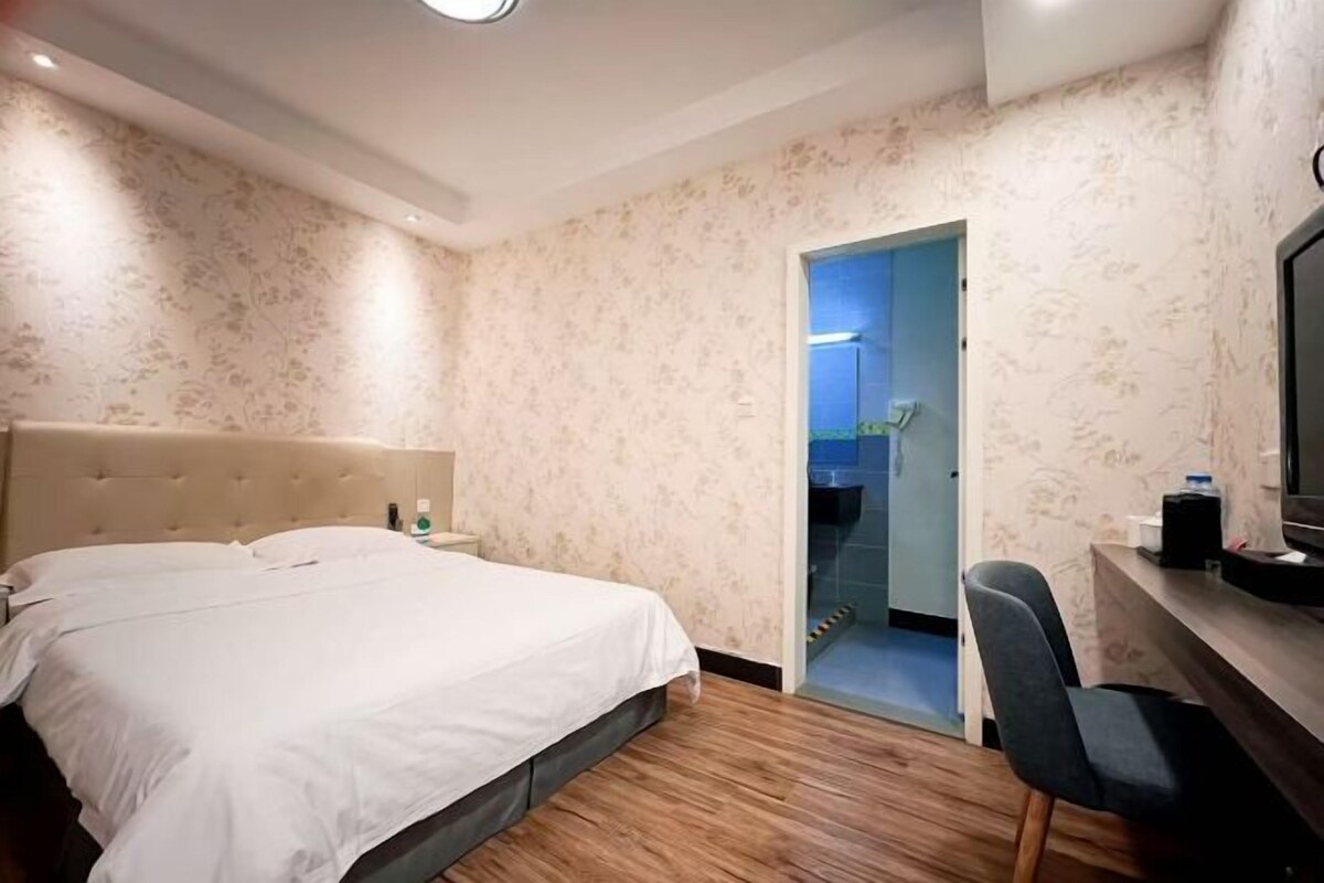 Una habitación de hotel con cama, escritorio, silla y televisión.