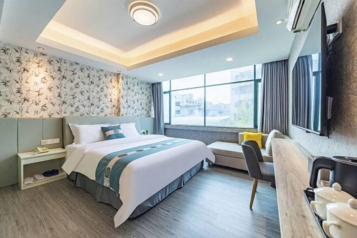 Une chambre d’hôtel moderne dotée d’un grand lit, d’un coin salon et d’une kitchenette.