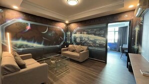 Una sala de estar moderna con un sofá, una mesa de centro y una pared con un mural de temática espacial.