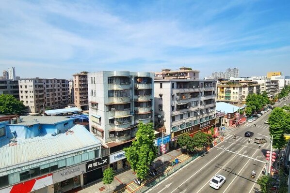 A multi-story building with balconies, a street view, and a clear sky.