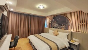 Habitación de hotel con cama, escritorio, silla, televisión y un cabecero decorativo.