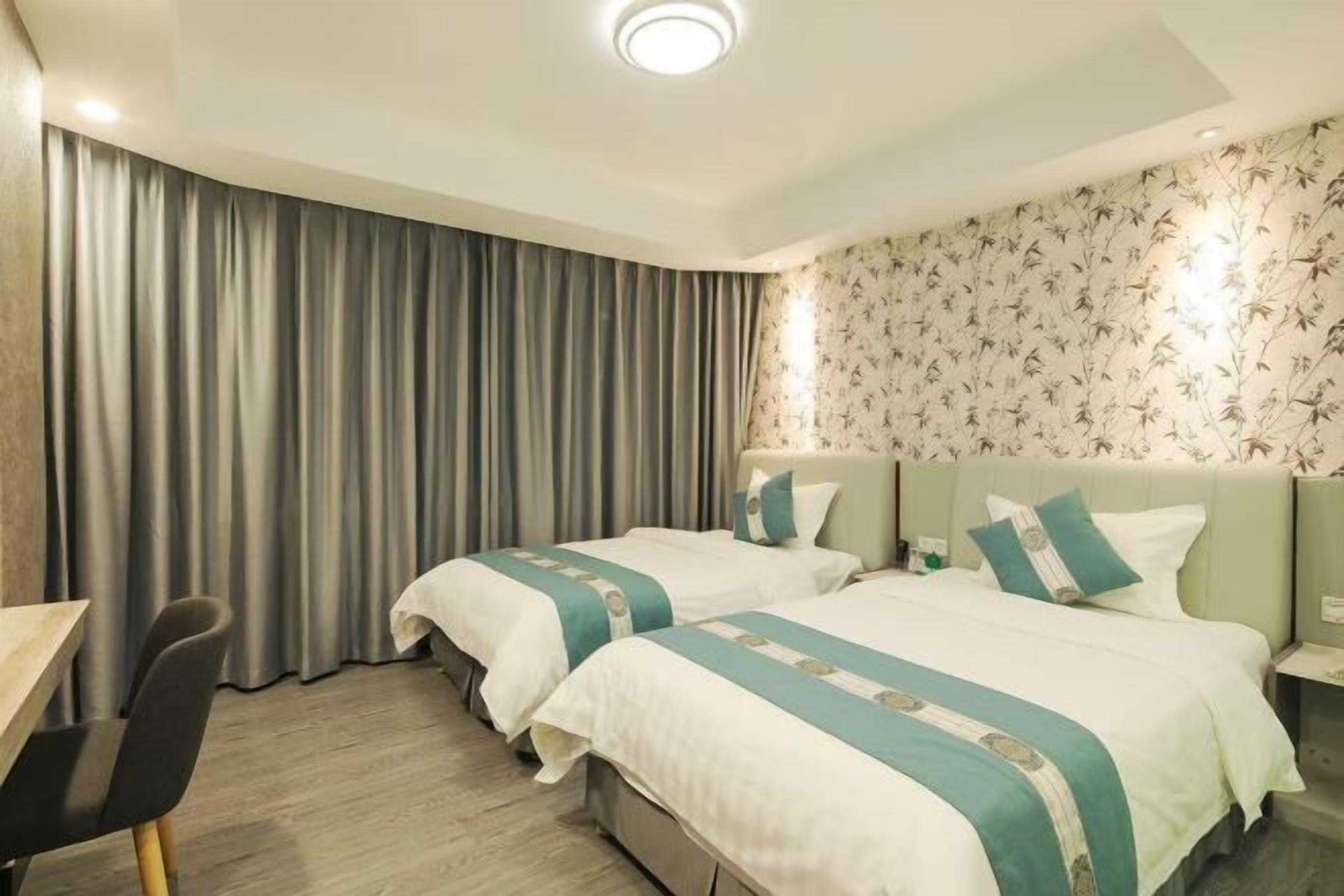 A hotel room with two beds, a desk, and a chair.
