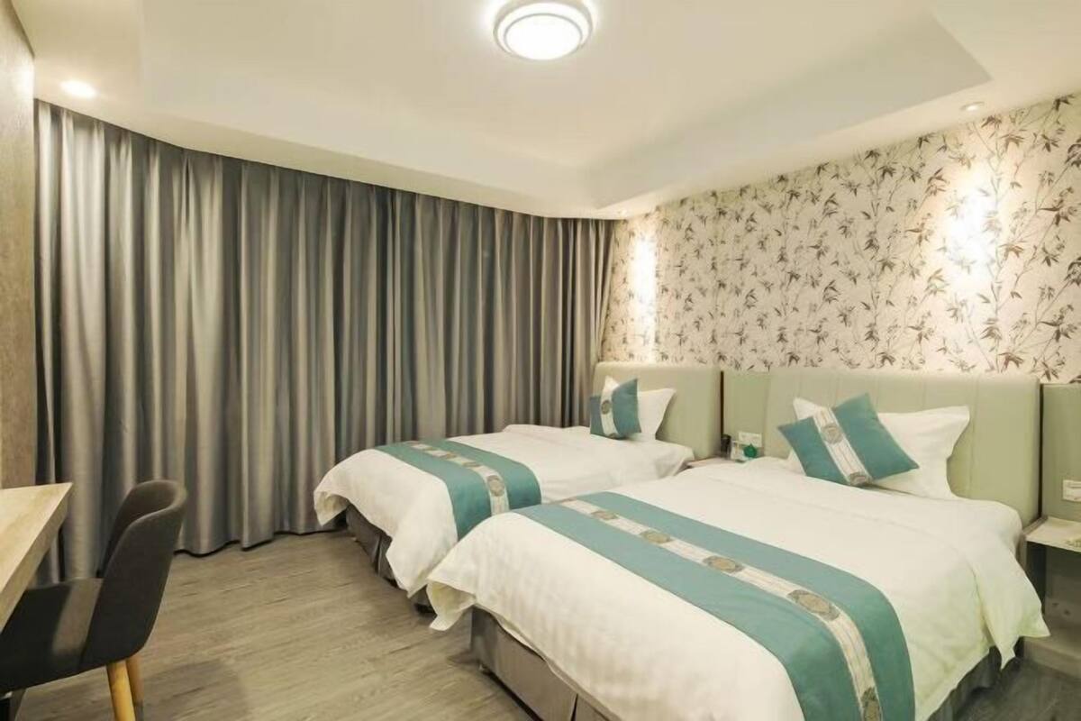 Une chambre d’hôtel avec deux lits, un bureau et une chaise.